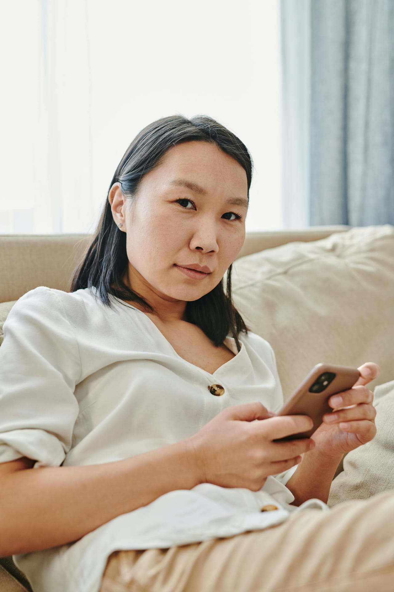 Customer at home holding a smartphone in a bright living room — placeholder editorial photo suggesting the camera-walk feature; UI ships Q3 2026.